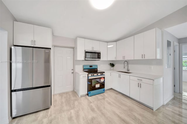 kitchen with a sink, light countertops, white cabinets, and stainless steel appliances