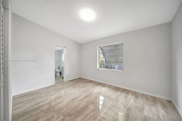 spare room featuring baseboards and lofted ceiling