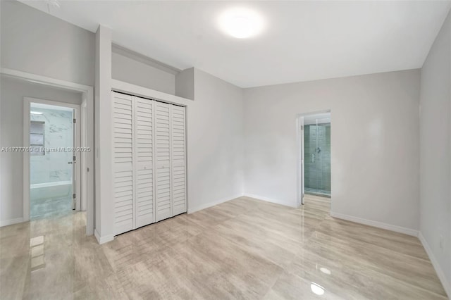 unfurnished bedroom with a closet, baseboards, light wood-type flooring, and ensuite bathroom