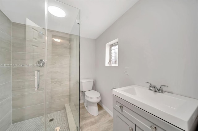 full bath featuring toilet, a stall shower, vanity, and baseboards