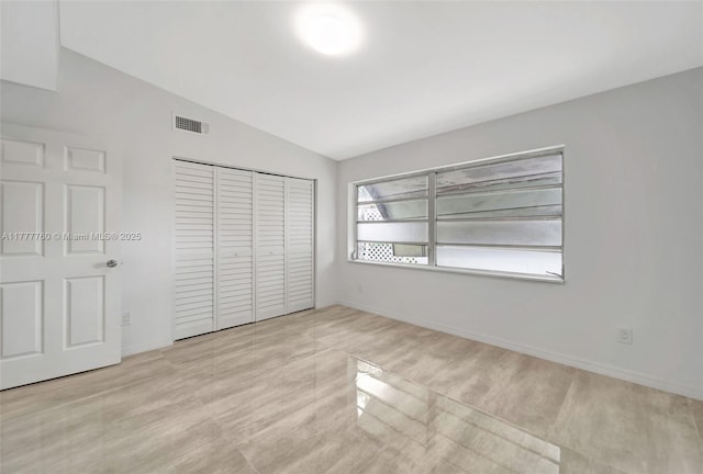 unfurnished bedroom with a closet, baseboards, lofted ceiling, and visible vents