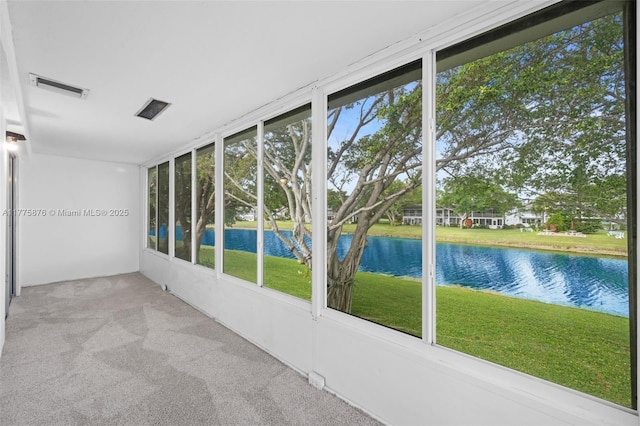 unfurnished sunroom featuring a water view, carpet, and visible vents