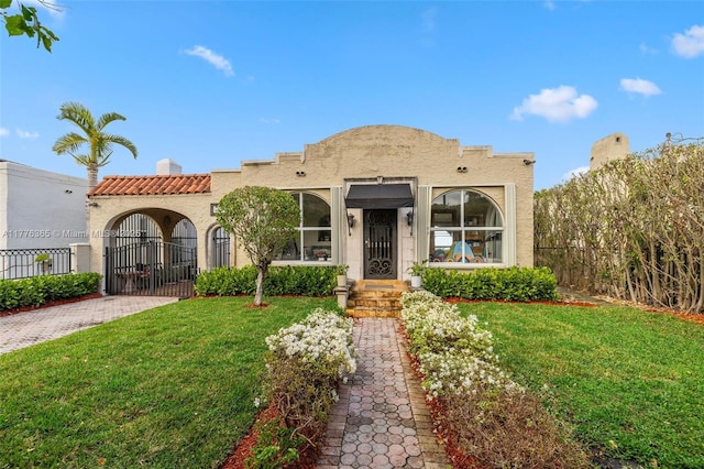 mediterranean / spanish house featuring a front yard, stucco siding, and fence