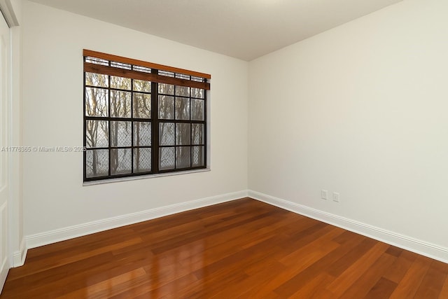 spare room with dark wood-style flooring and baseboards