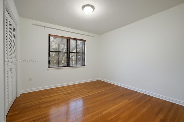 unfurnished bedroom with a closet, baseboards, and wood finished floors