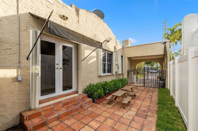 exterior space featuring a gate, fence, stucco siding, and french doors