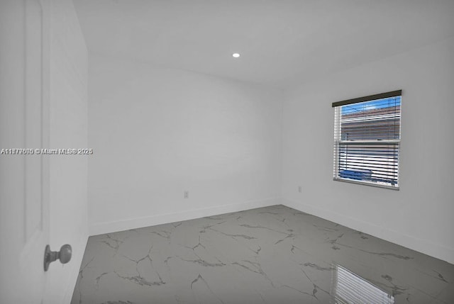 spare room with baseboards, recessed lighting, and marble finish floor