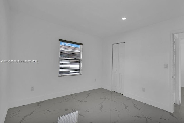 spare room featuring recessed lighting, marble finish floor, and baseboards