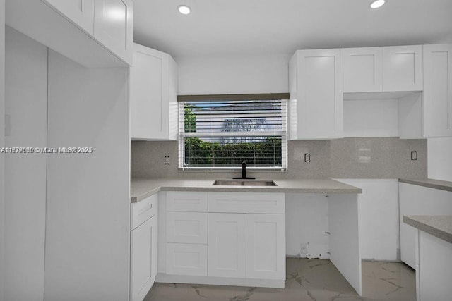 kitchen with white cabinetry, recessed lighting, marble finish floor, and a sink