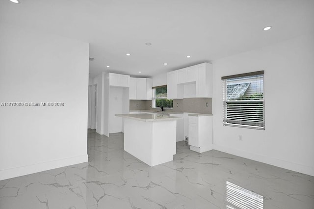 kitchen featuring baseboards, white cabinetry, a kitchen island, and marble finish floor