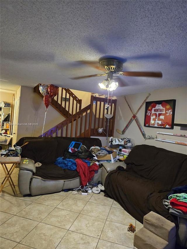 living area with tile patterned flooring, a ceiling fan, and a textured ceiling