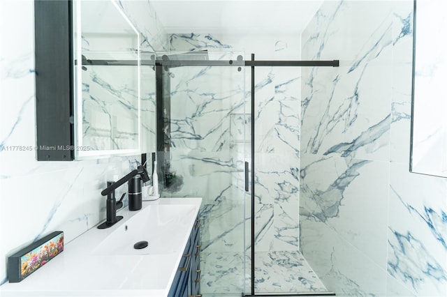bathroom featuring tile walls, a marble finish shower, and vanity