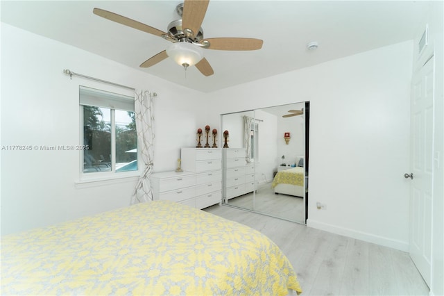 bedroom featuring light wood finished floors, baseboards, visible vents, a closet, and ceiling fan