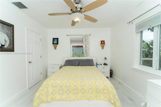bedroom featuring baseboards, a ceiling fan, visible vents, and light wood-style flooring