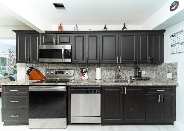 kitchen featuring visible vents, decorative backsplash, stainless steel appliances, and a sink