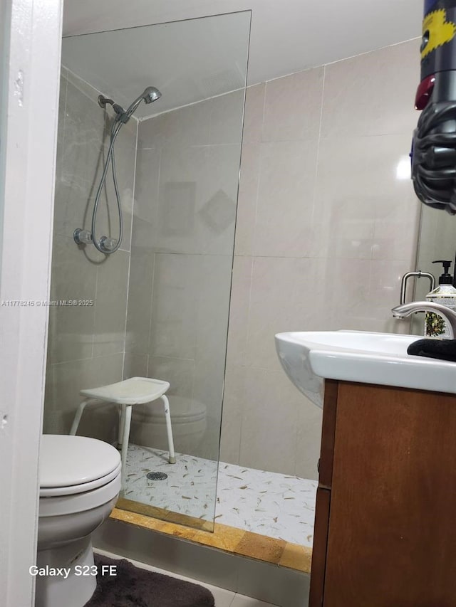 bathroom featuring tile walls, toilet, vanity, and tiled shower