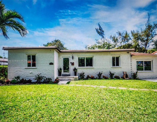 ranch-style home featuring a front lawn and concrete block siding