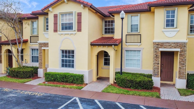view of front of property featuring a tile roof, stucco siding, and uncovered parking