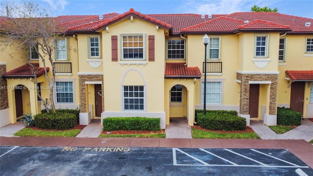 view of property featuring a tiled roof, stucco siding, and uncovered parking