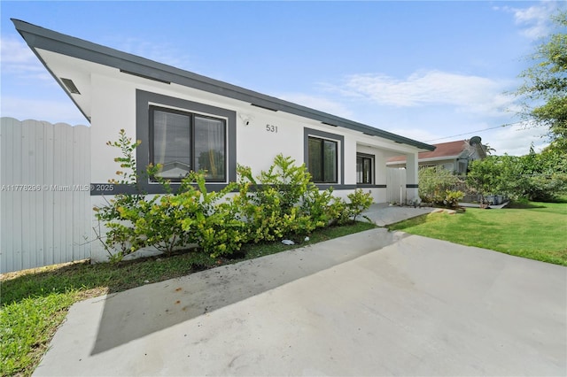 view of front of house with a patio, a front yard, and stucco siding
