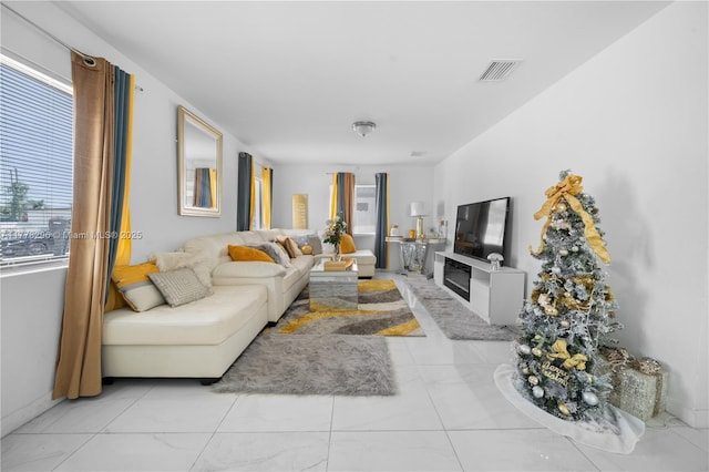 living area featuring a glass covered fireplace, visible vents, and baseboards