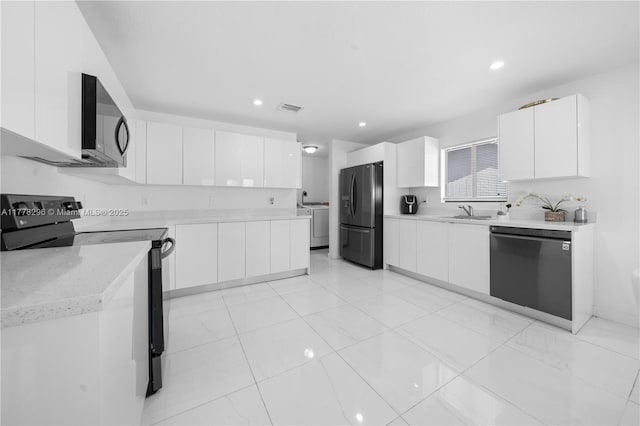 kitchen featuring a sink, visible vents, freestanding refrigerator, electric range, and dishwashing machine