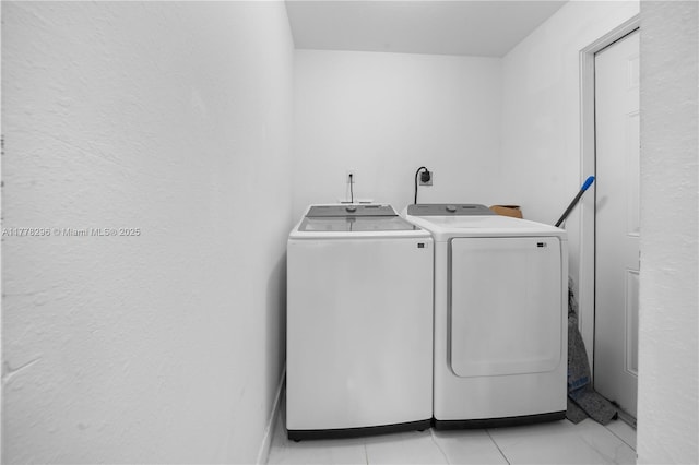 laundry room with light tile patterned floors, washer and clothes dryer, and laundry area