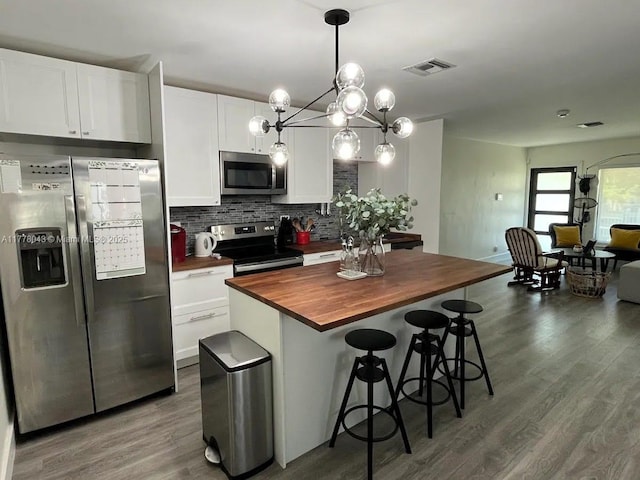 kitchen with butcher block countertops, stainless steel appliances, dark wood-style floors, visible vents, and white cabinets