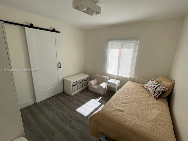 bedroom with a barn door and dark wood finished floors