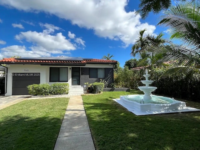 view of front of property with a front lawn, roof mounted solar panels, a tiled roof, and a garage