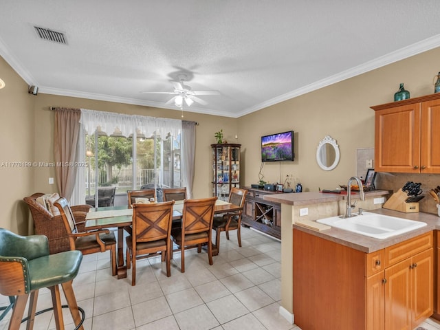 kitchen with light tile patterned flooring, ceiling fan, a sink, and light countertops