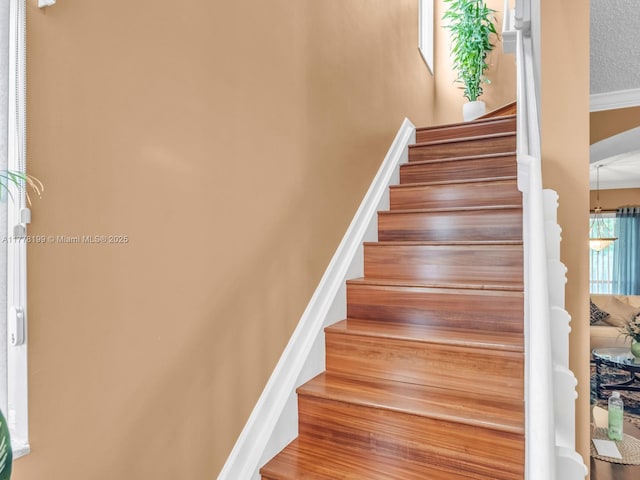 staircase featuring crown molding and baseboards