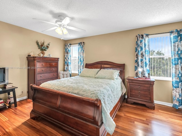 bedroom with a textured ceiling, baseboards, ceiling fan, and wood finished floors