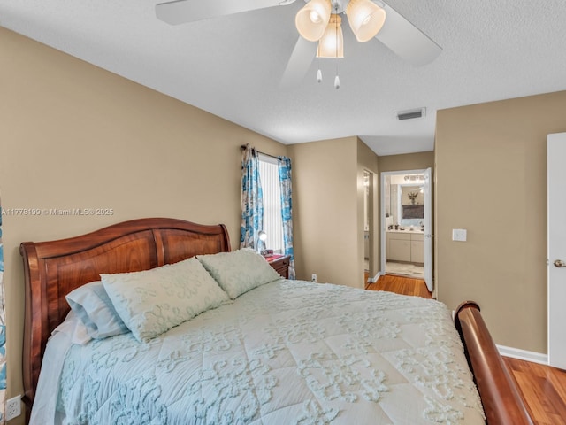 bedroom with visible vents, wood finished floors, ceiling fan, and ensuite bathroom