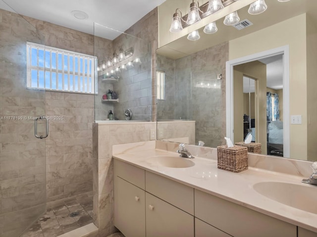 bathroom with double vanity, a sink, tiled shower, and visible vents