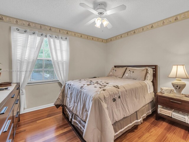 bedroom with baseboards, wood finished floors, ceiling fan, and a textured ceiling