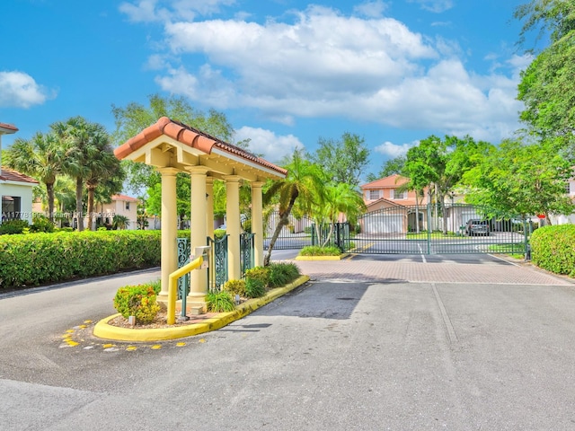 view of road with a gated entry, a gate, and curbs