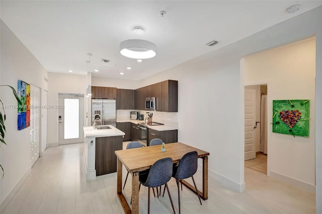 4740 NW 84th Ct Unit 32, Doral, FL 33166 - kitchen with light countertops, visible vents, a kitchen island with sink, dark brown cabinetry, and appliances with stainless steel finishes