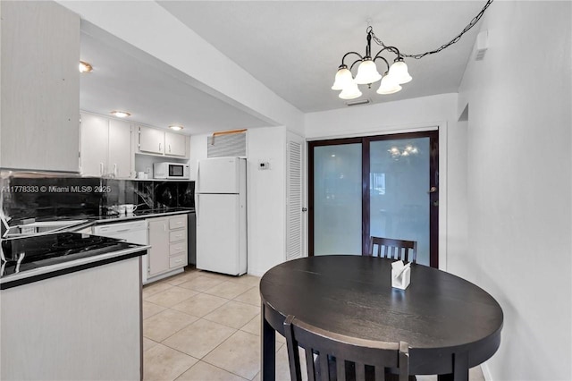 kitchen featuring an inviting chandelier, dark countertops, white cabinetry, and white appliances