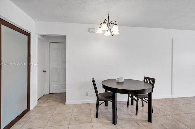 dining space featuring light tile patterned flooring, baseboards, a notable chandelier, and a textured ceiling