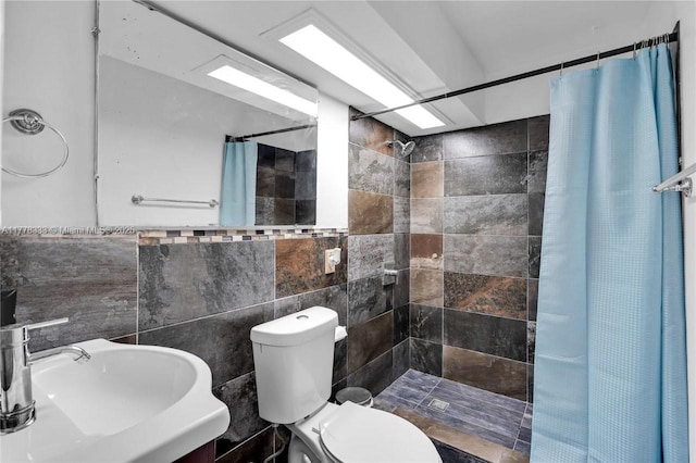 bathroom featuring toilet, tile walls, a tile shower, and a sink