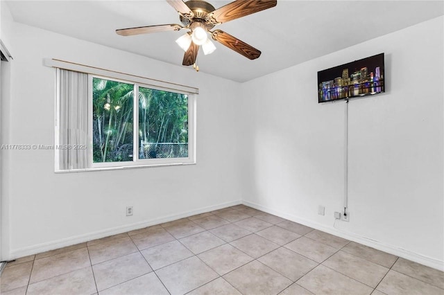 unfurnished room with light tile patterned flooring, a ceiling fan, and baseboards