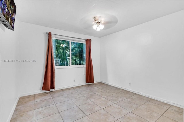 empty room featuring baseboards, ceiling fan, and light tile patterned floors