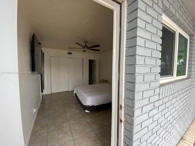 tiled bedroom featuring a ceiling fan, visible vents, and a closet