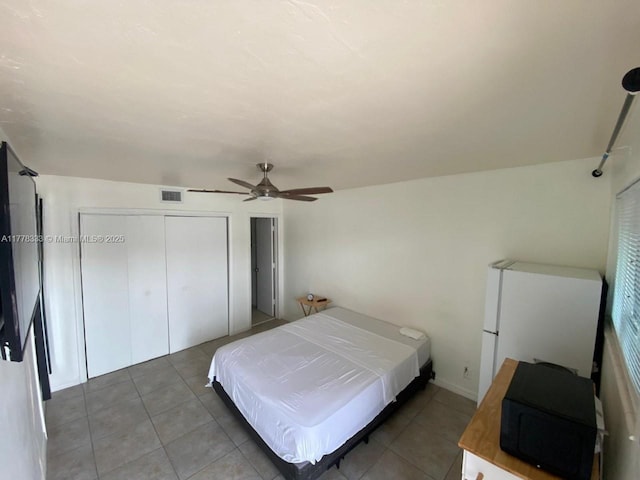 tiled bedroom featuring ceiling fan, a closet, and visible vents