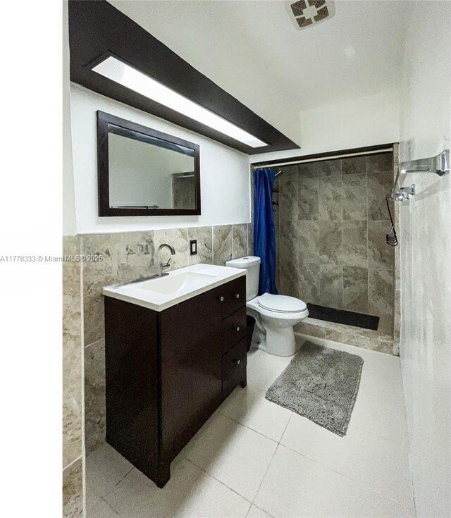 full bathroom featuring visible vents, vanity, tile patterned flooring, tile walls, and tiled shower