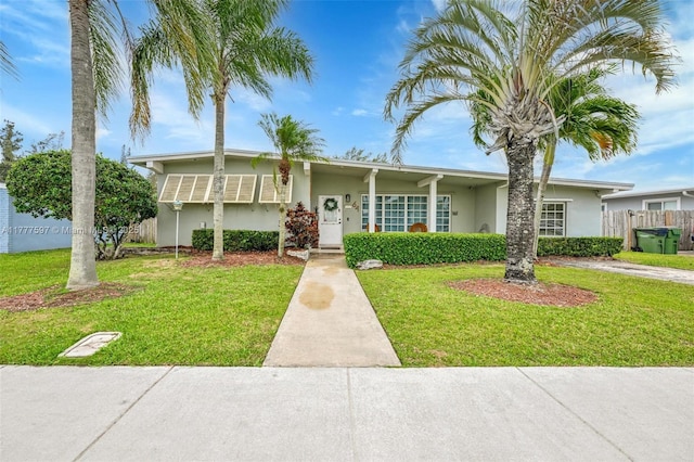 view of front of house featuring stucco siding, fence, and a front yard