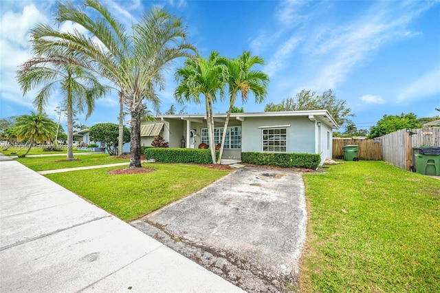 ranch-style house with stucco siding, fence, and a front lawn