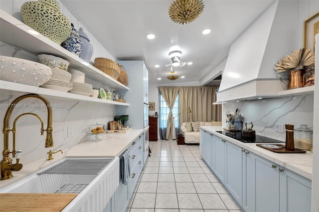 kitchen featuring light tile patterned floors, open shelves, a sink, custom range hood, and black electric cooktop
