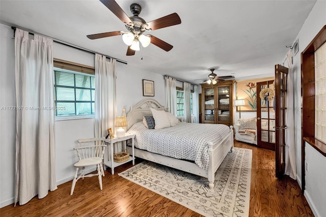 bedroom featuring wood finished floors, baseboards, and multiple windows